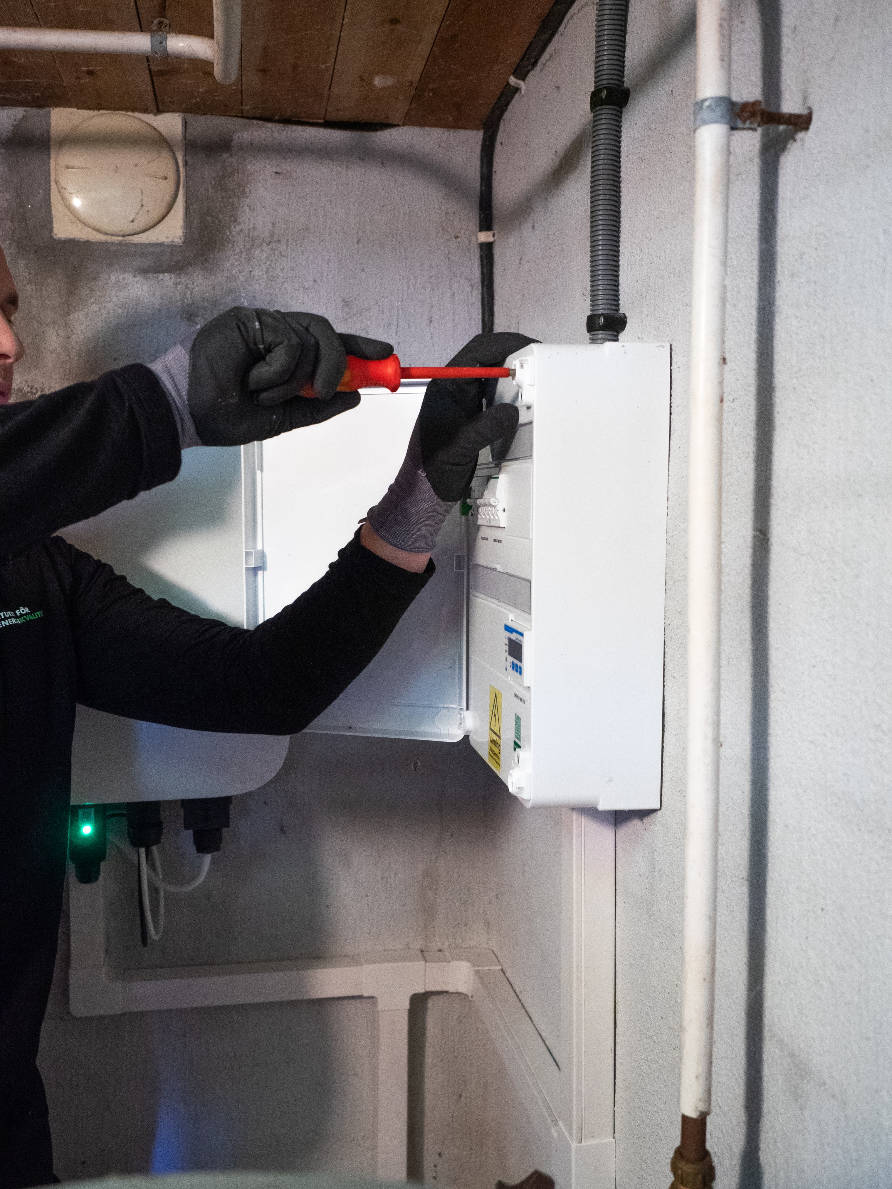Besiktningsperson kontrollerar en väggmonterad installation